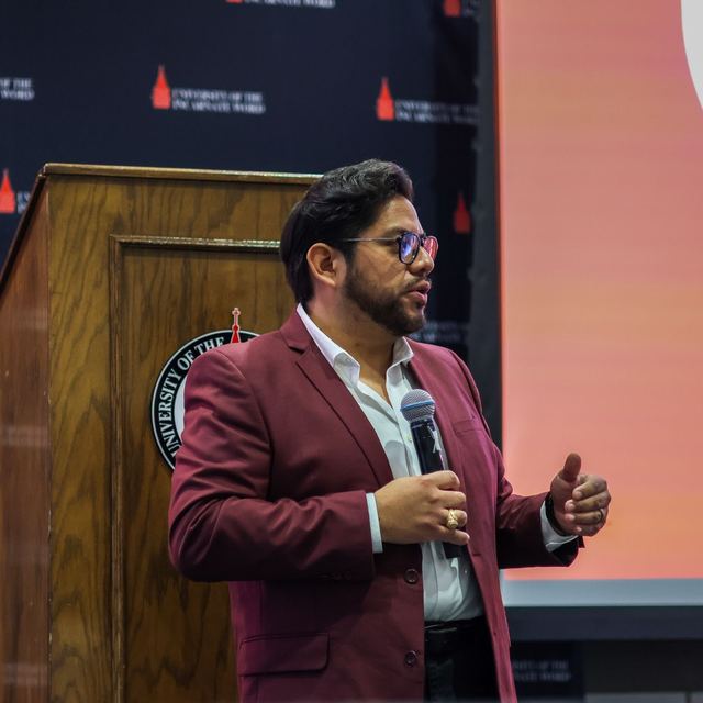 Carlos de León speaking at a podium